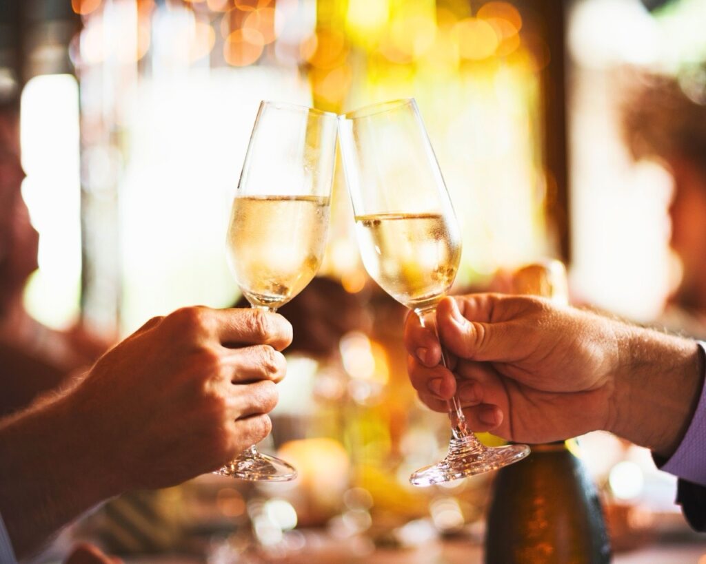 A couple enjoying a glass of prosecco and saying cheers to having a nice time at the summer offer at the snooty fox tetbury.