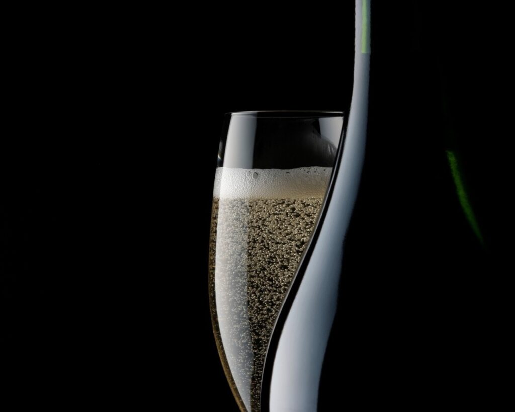 glass of prosecco and bottle on a black background